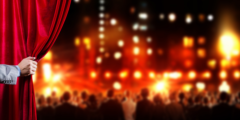 Hand of businessman opening red velvet curtain